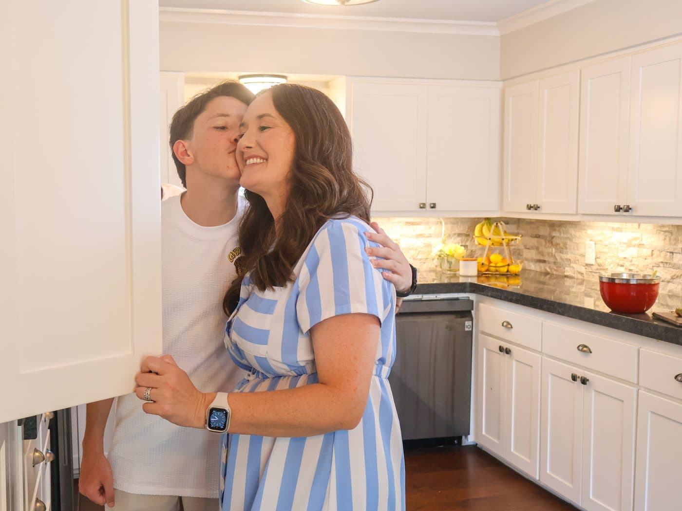 Khota kisses his mom Amanda on the cheek in the family kitchen