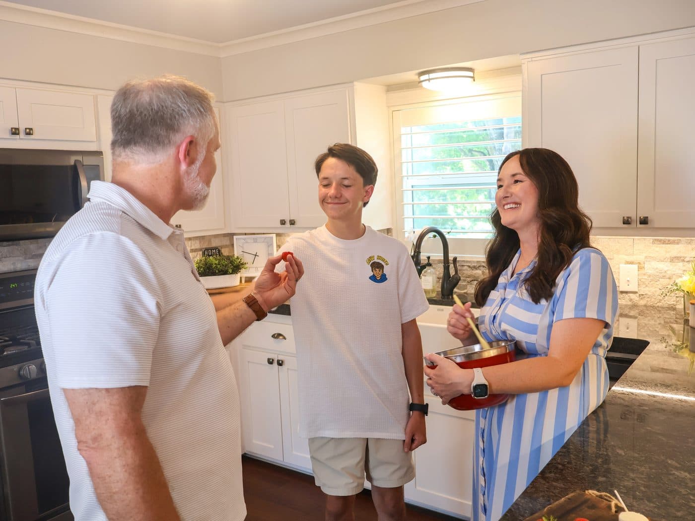 Rohmel, Khota, and Amanda laughing together while mixing a batch in the kitchen